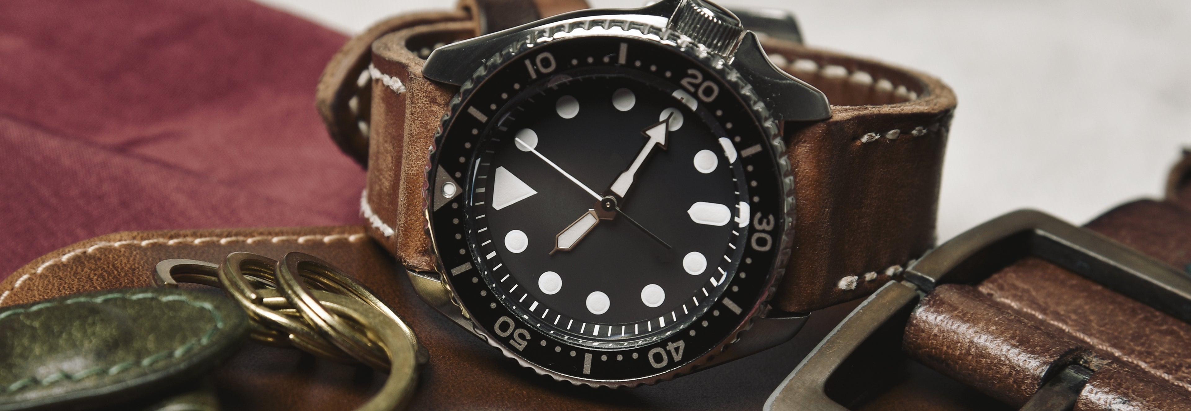 Watch with brown leather strap and black dial on a textured surface