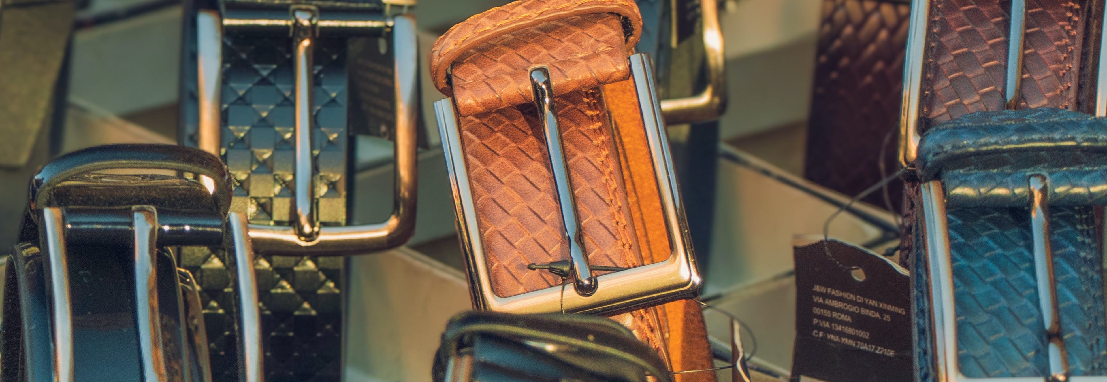 Close-up of various leather belts with metal buckles on a neutral background