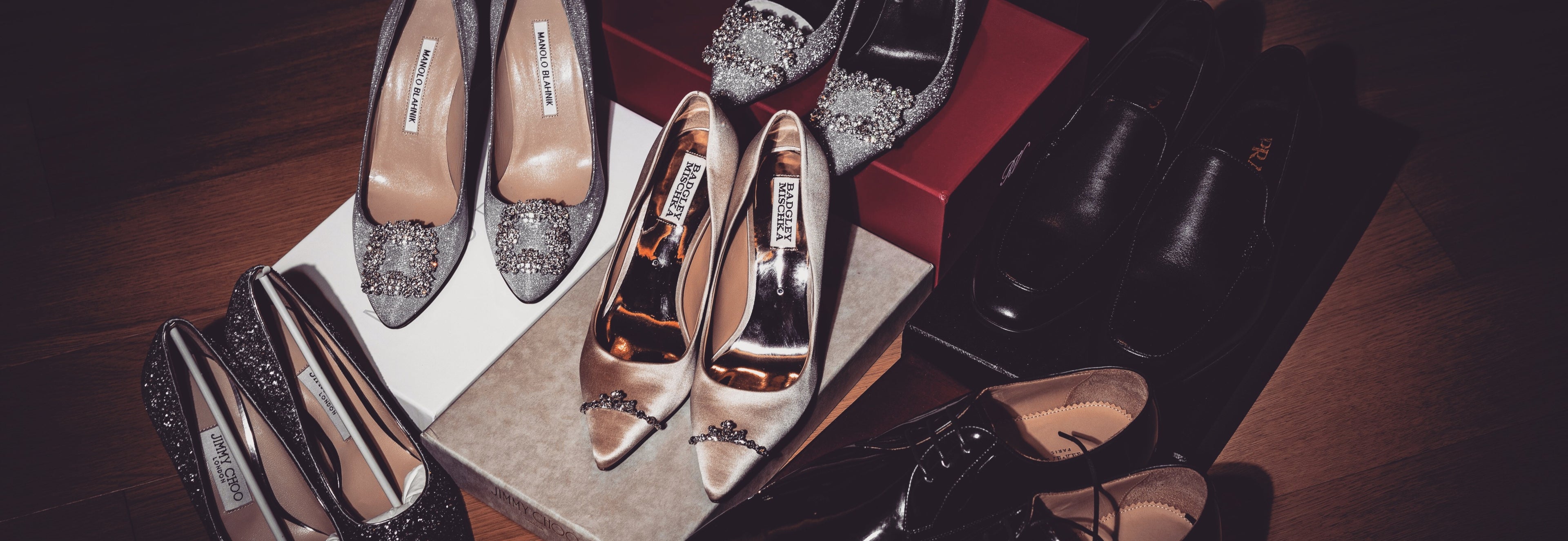 Pair of high-heeled shoes with glittery soles on a wooden surface.