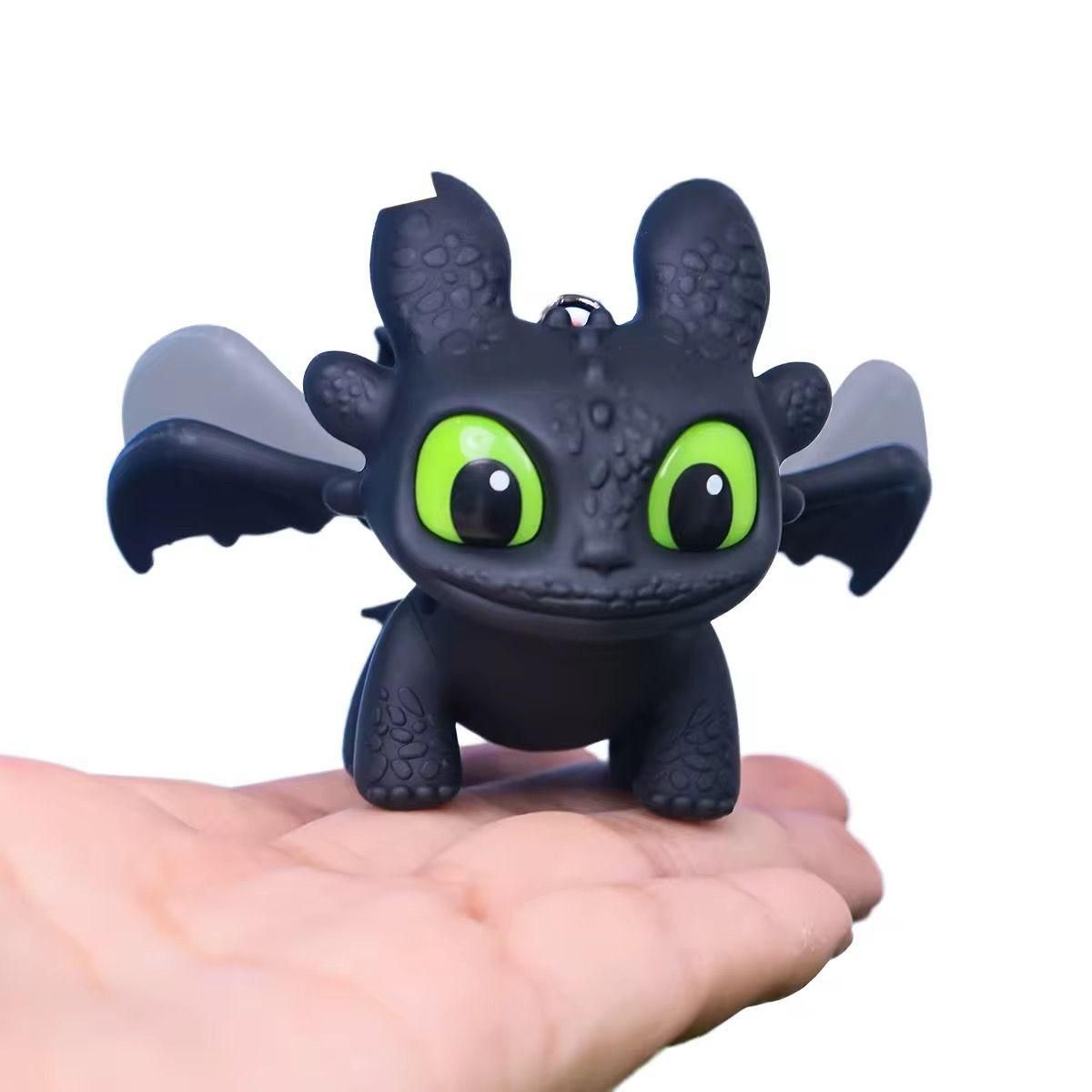 Toy dragon figure with green eyes held in a hand on a white background
