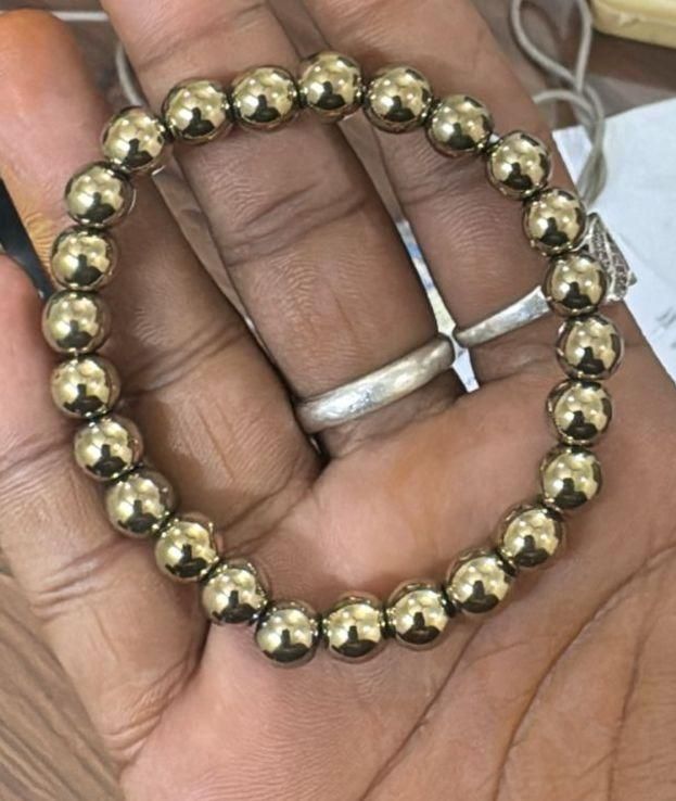Gold beaded bracelet on a hand with a silver ring