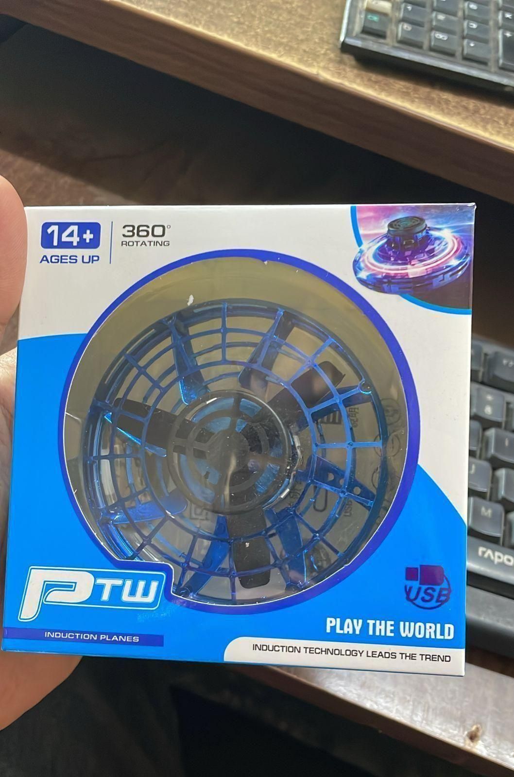 Box of a toy with blue and white design, held by a hand on a desk.