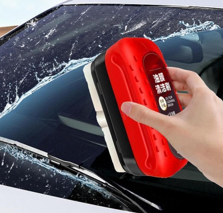 Person using a car window cleaning tool on a car windshield