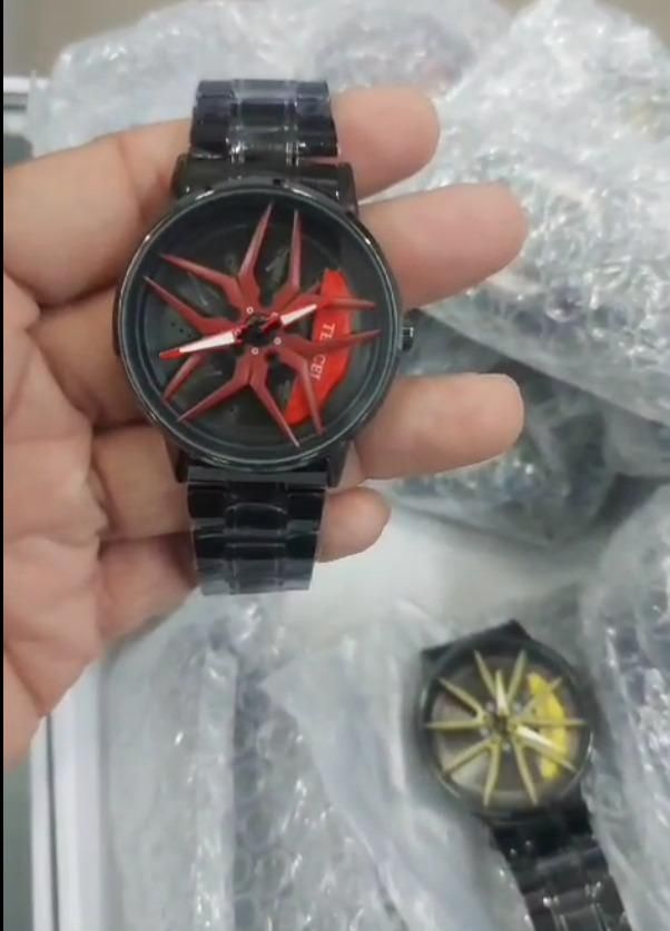 Black watch with red face held by a hand, bubble wrap in the background