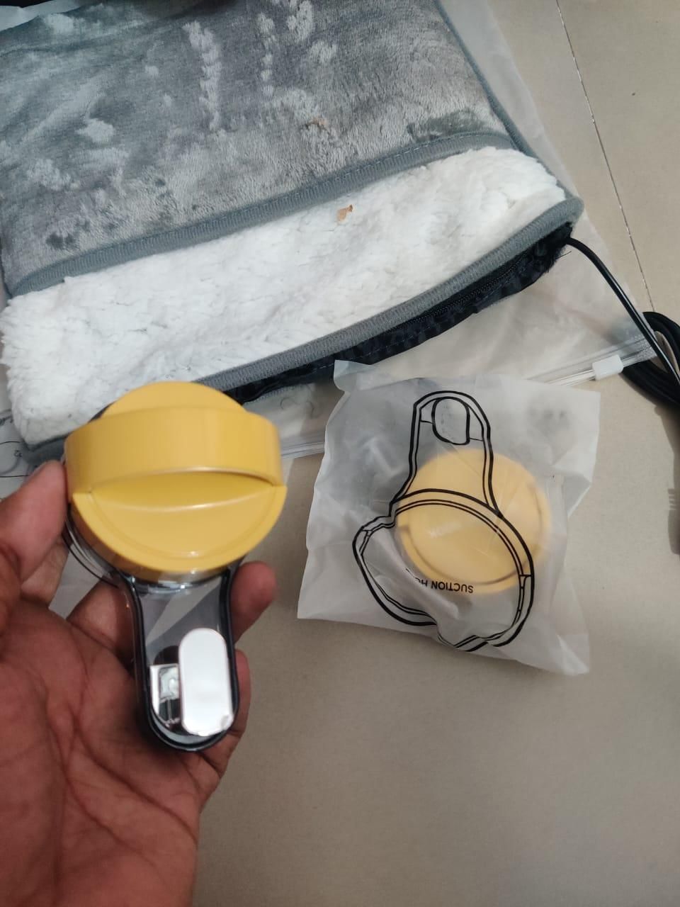Hand holding a yellow and silver tool with a branded bag in the background