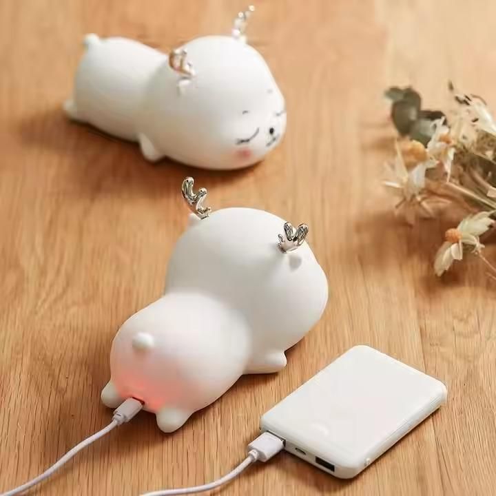 Silicone cow-shaped device with a power bank on a wooden surface