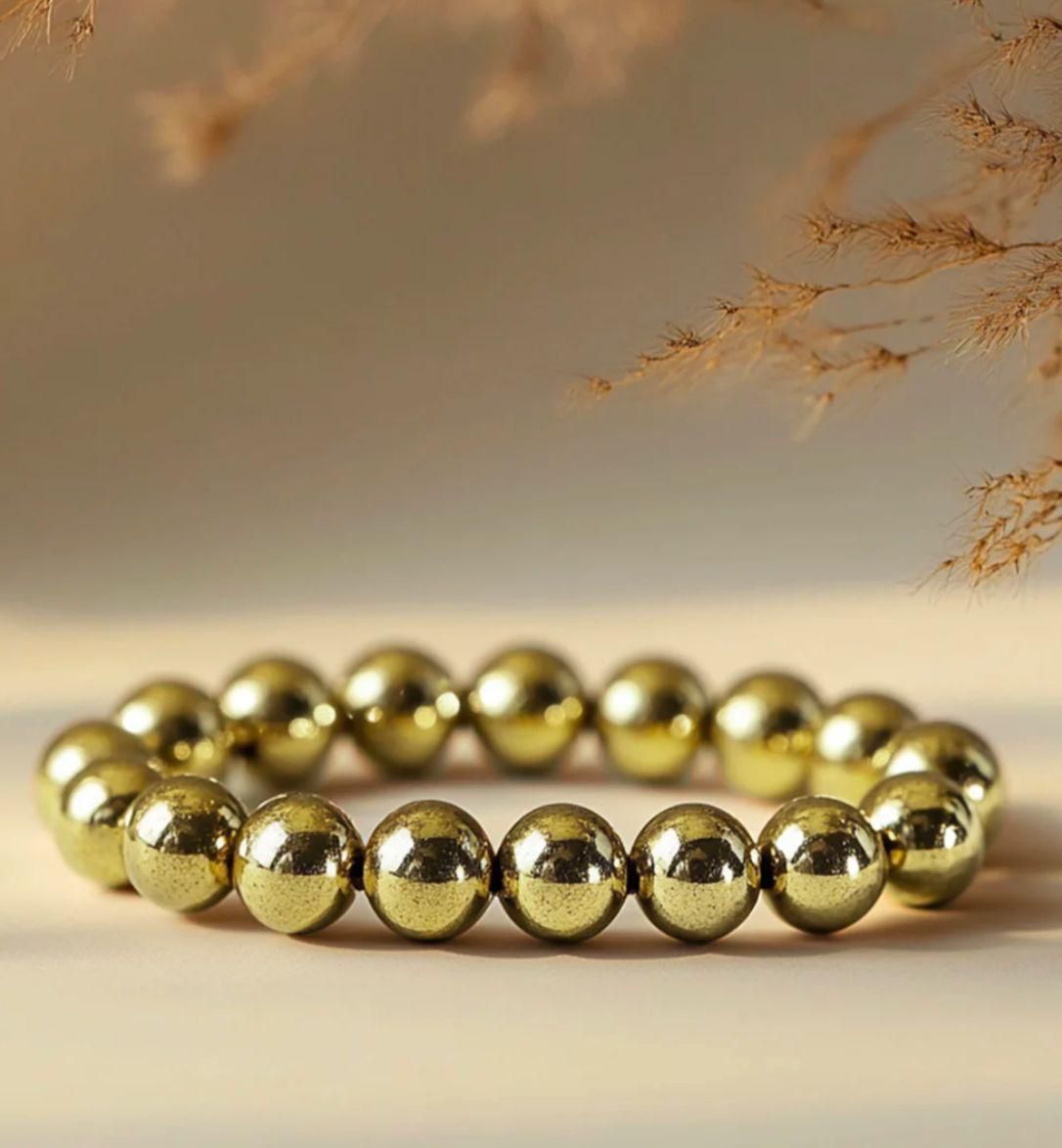 Gold beaded bracelet on a neutral background with dried plants