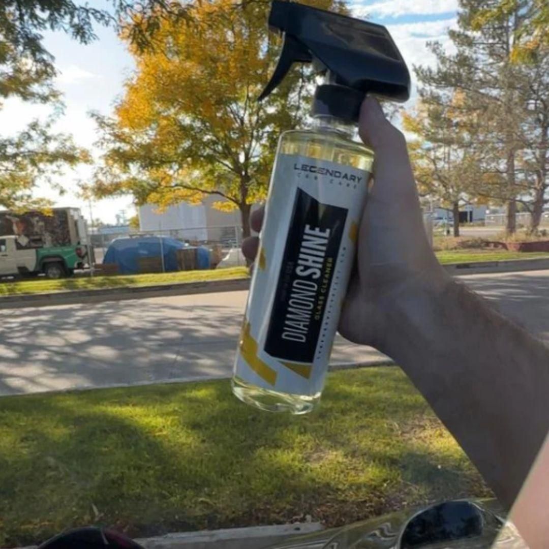 Hand holding a bottle of Diamond Shine car care product with a blurred outdoor background