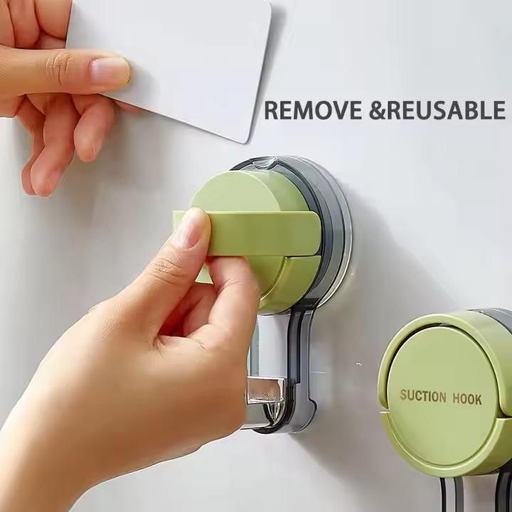 Hand using a green suction hook to remove a paper from a white surface.
