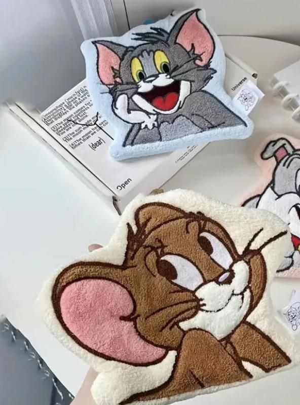 Plush toys of cartoon characters on a surface with a book in the background