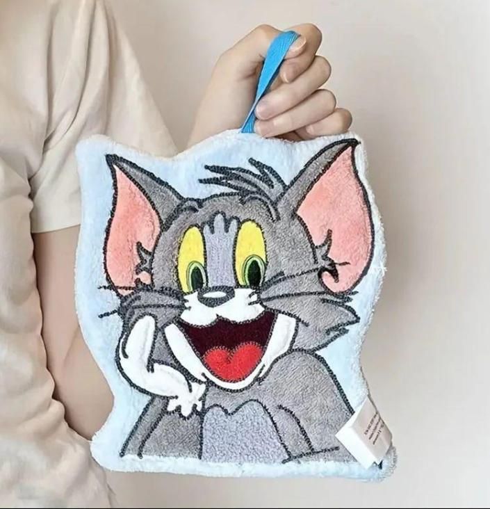 Plush toy shaped like a cartoon cat held by a person against a plain background
