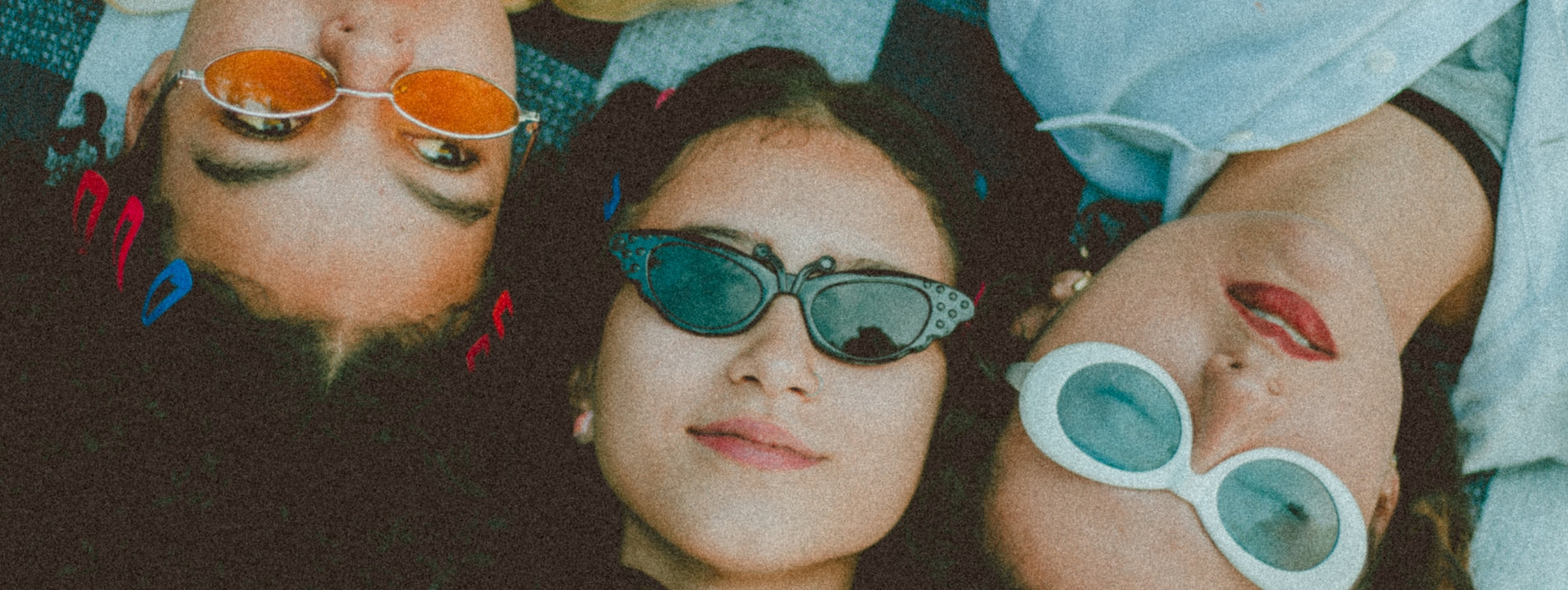Three people wearing colorful sunglasses with a blurred background